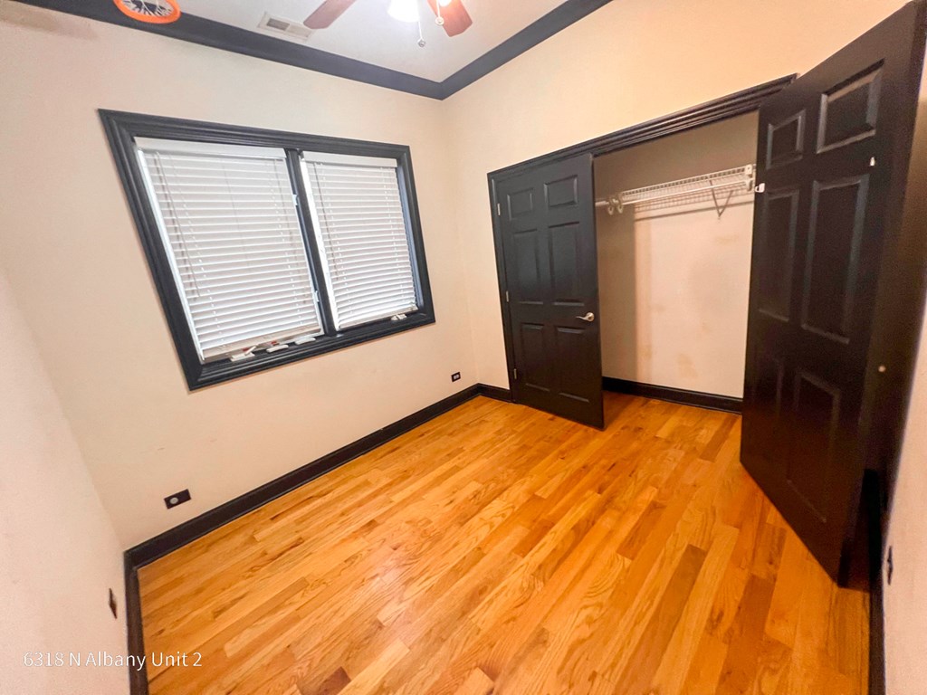 a bedroom with wood floors and a closet and a window