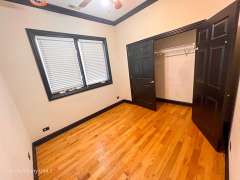 a bedroom with wood floors and a closet and a window