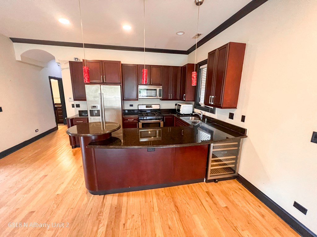 a kitchen with wooden floors and stainless steel appliances
