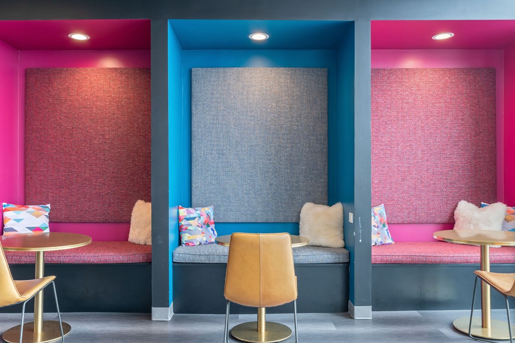 the seating area of a colorful restaurant with chairs and cushions