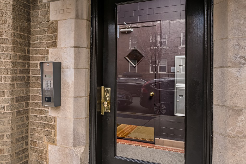 the front door of a building with a reflection of a car in the window