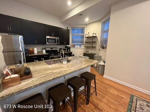 A kitchen with granite countertops and black cabinets.