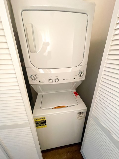A white dryer and washer are sitting in a small space.