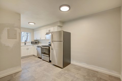 A kitchen with a refrigerator, microwave, and oven.