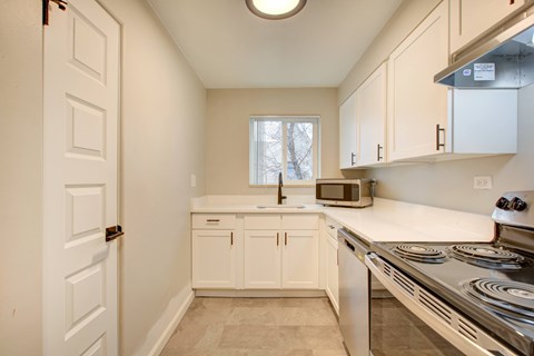A kitchen with white cabinets and a stainless steel stove.