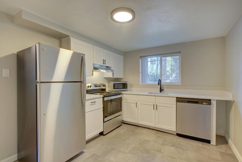 A kitchen with a refrigerator, oven, and microwave.