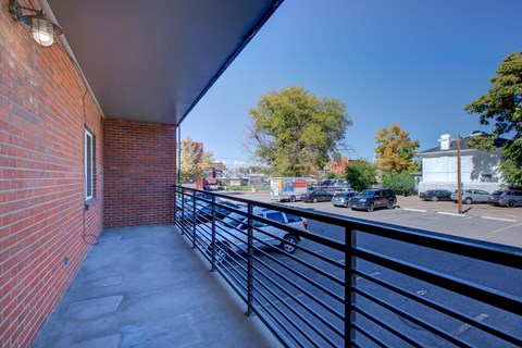 A balcony with a black railing and a brick wall.