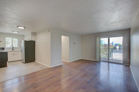 A room with wooden floors and a sliding glass door leading to a balcony.
