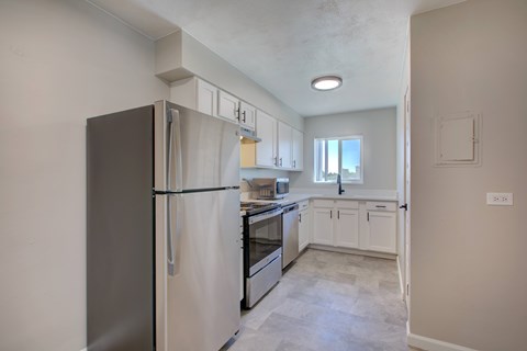 A kitchen with a refrigerator, oven, and cabinets.