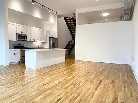 A kitchen with white cabinets and a wooden floor.