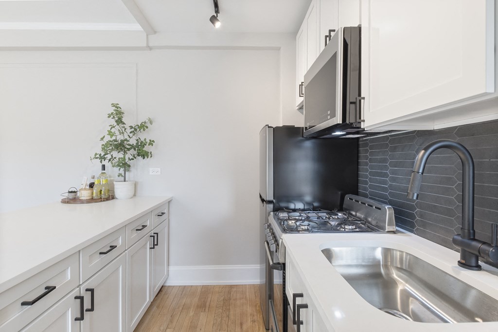 a kitchen with white cabinets and a stainless steel sink and stove