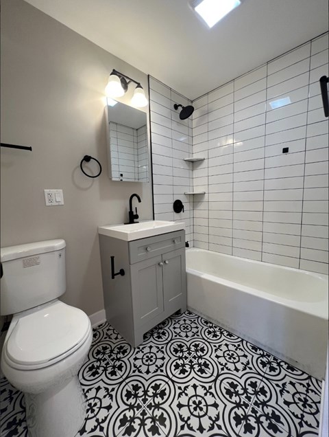 A white toilet sits next to a sink in a black and white tiled bathroom.