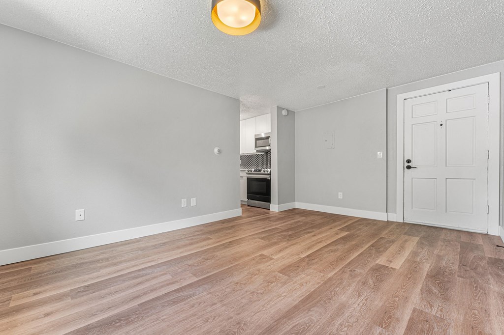 a living room with a hardwood floor and a doorway into a kitchen