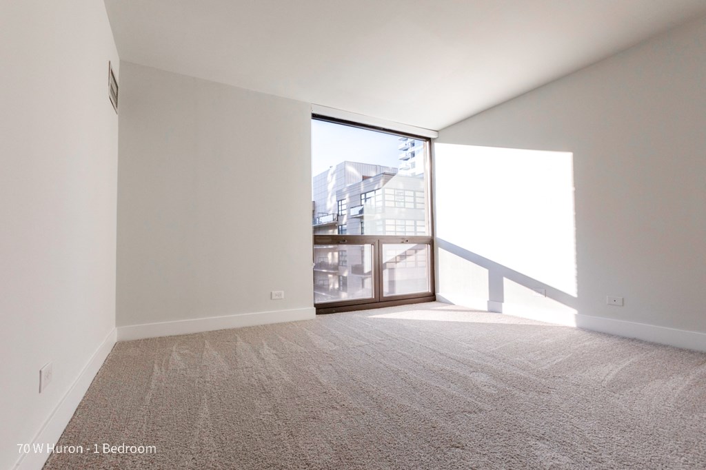 an empty living room with a large window and carpet