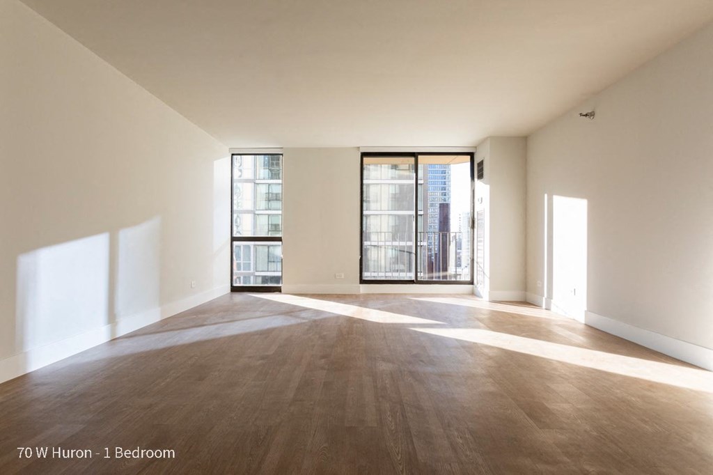 an empty living room with wood flooring and a door to a balcony