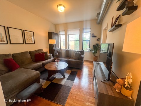 A living room with a grey couch, a coffee table, and a flat screen TV.