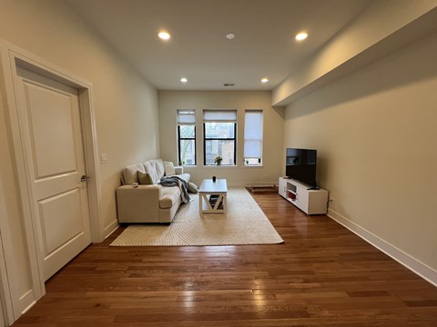 A living room with a white couch and a wooden floor.