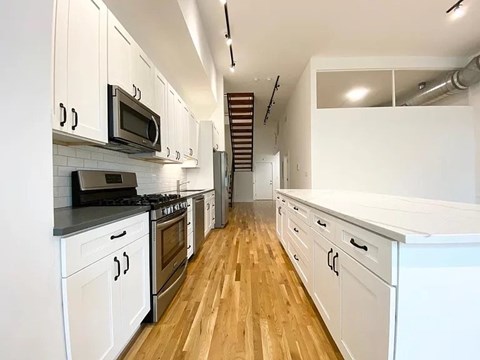 A kitchen with white cabinets and a wooden floor.