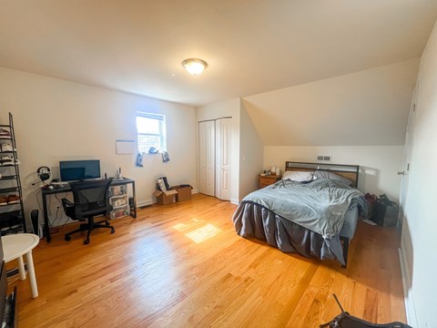 A bedroom with a bed, desk, and chair.