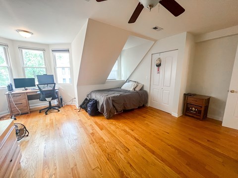A room with a bed, desk, and chair.