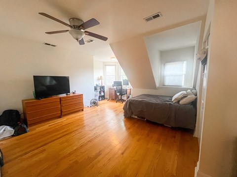 A bedroom with a bed, dresser, and television.