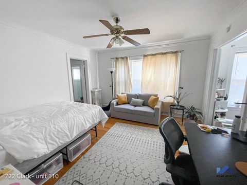 a bedroom and living room with a bed and a ceiling fan