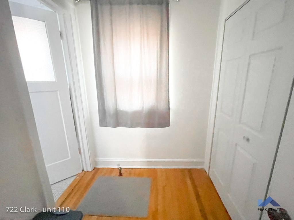 a window with a curtain on a wall in a room with wooden floors