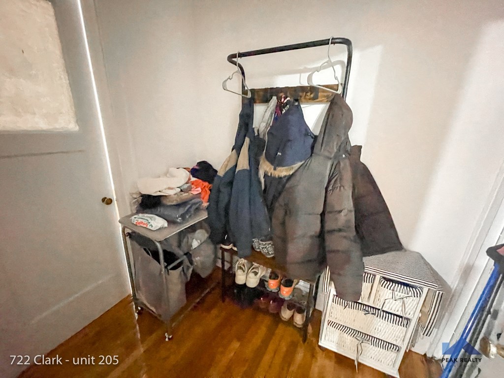 the coat rack in the corner of a room with clothes hanging on it