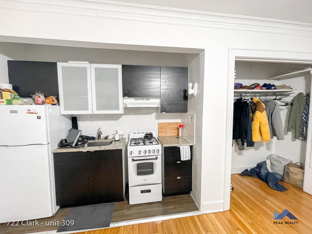 a small kitchen with white appliances and black cabinets and a white refrigerator