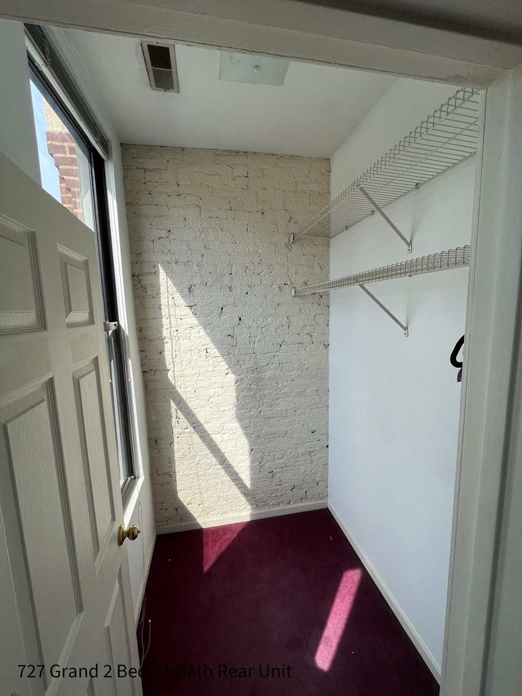 a room with a red carpet and a white brick wall