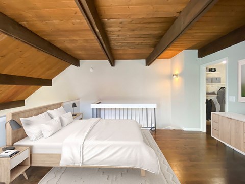 A bedroom with a bed, nightstand, and a wooden ceiling.