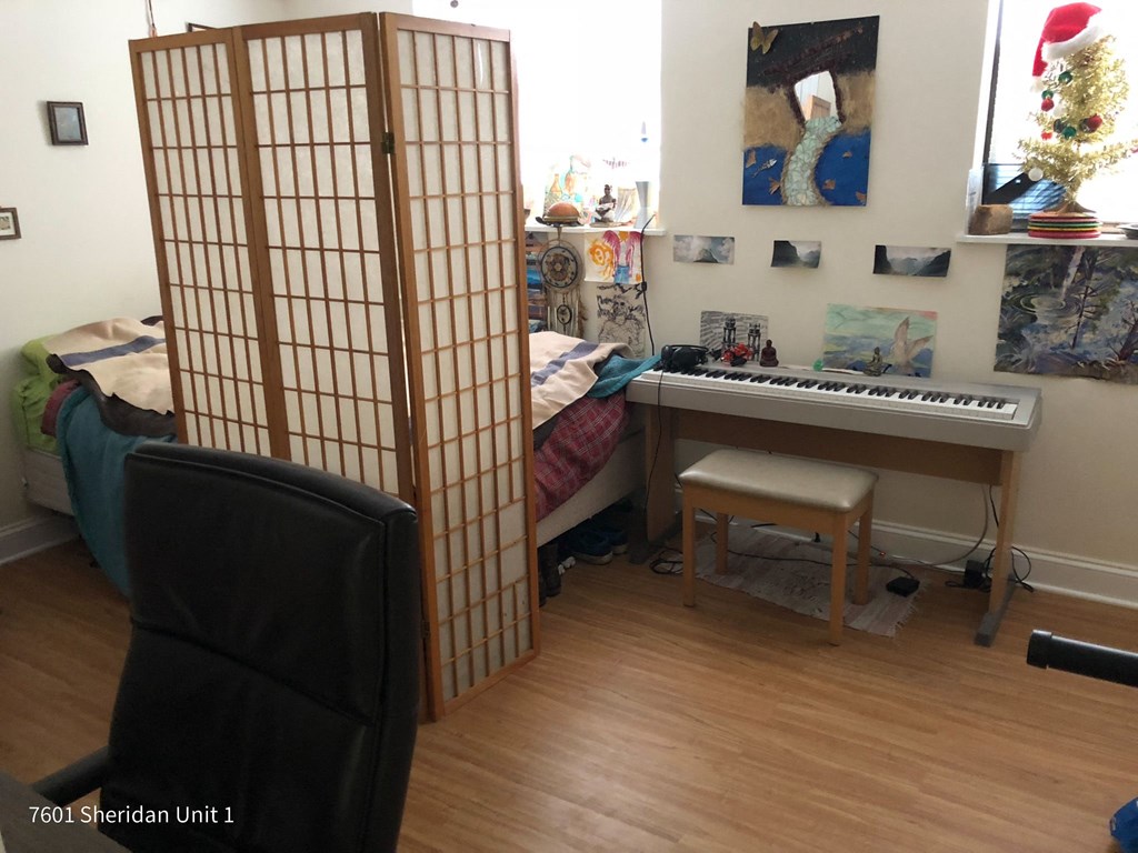 a room with a piano and a room divider with a bed and a desk