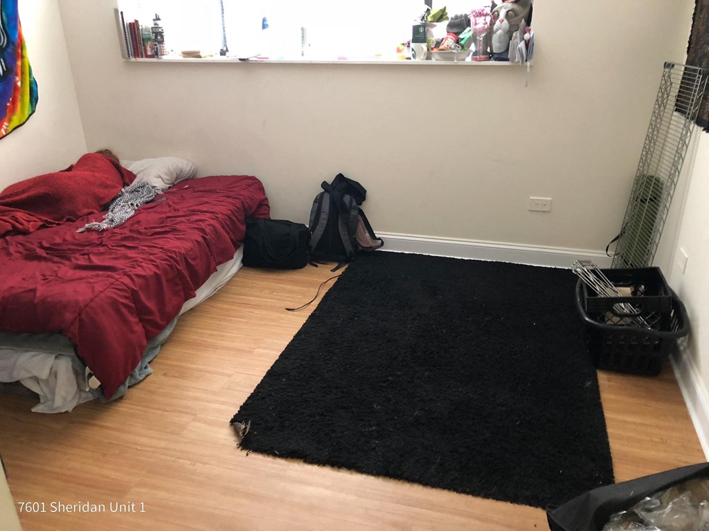 a bedroom with a bed and a black rug on the floor