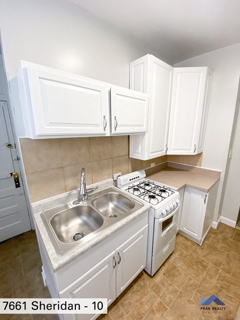 a kitchen with white cabinets and a sink and a stove