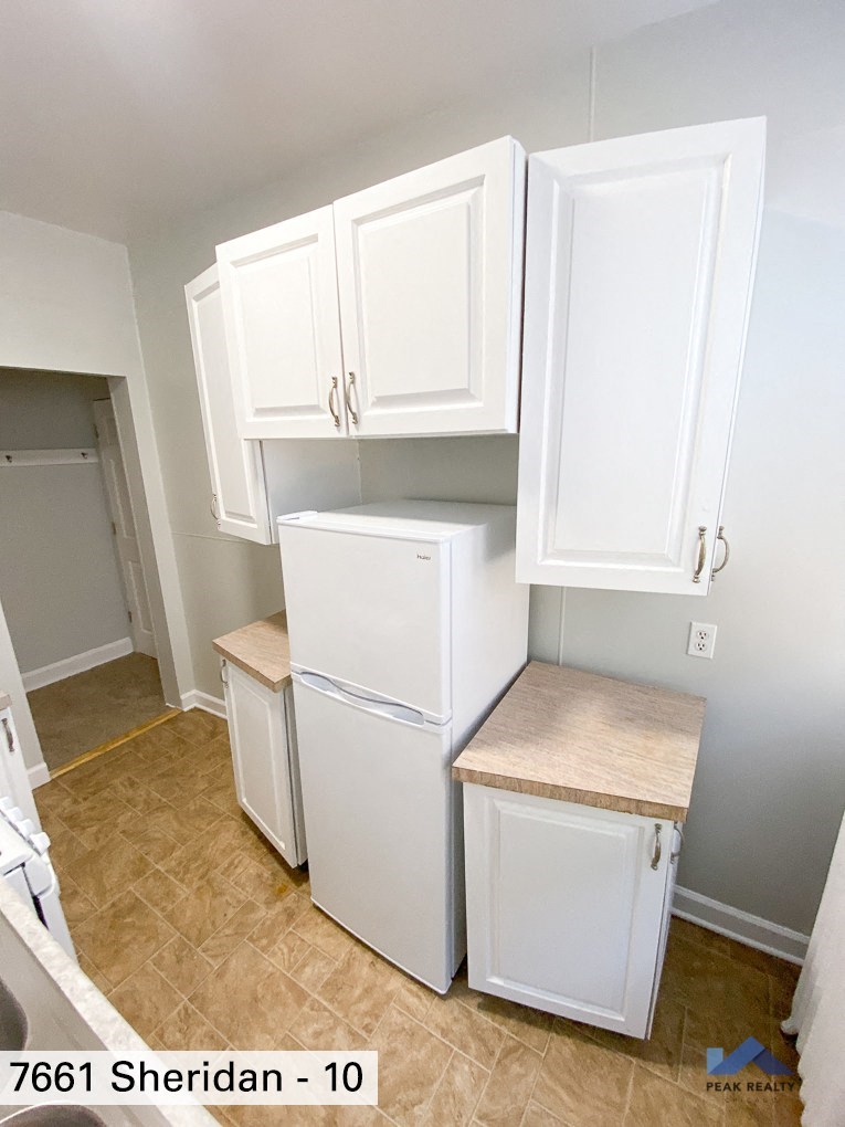 a small kitchen with white cabinets and a white refrigerator