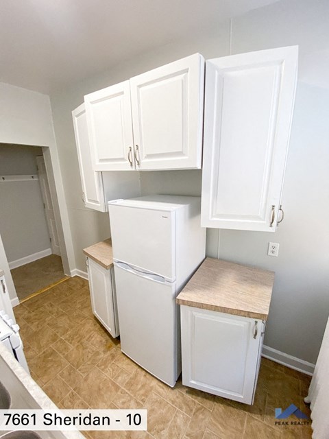 a small kitchen with white cabinets and a white refrigerator