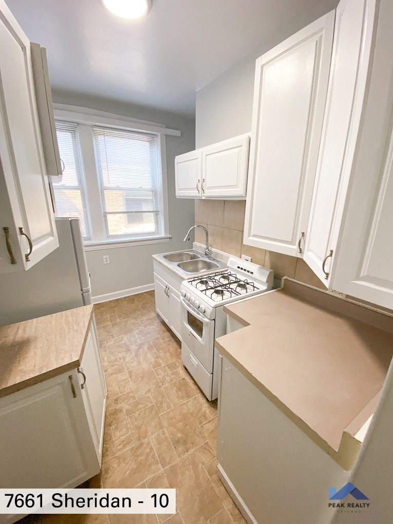 a kitchen with white cabinets and a stove and a window
