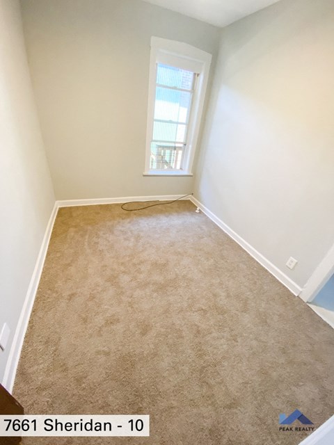 an empty room with a carpeted floor and a window