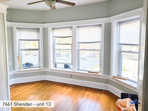 four windows in a room with a wooden floor and a ceiling fan