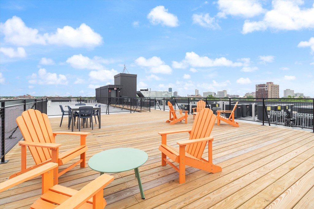 a rooftop deck with orange chairs and a table
