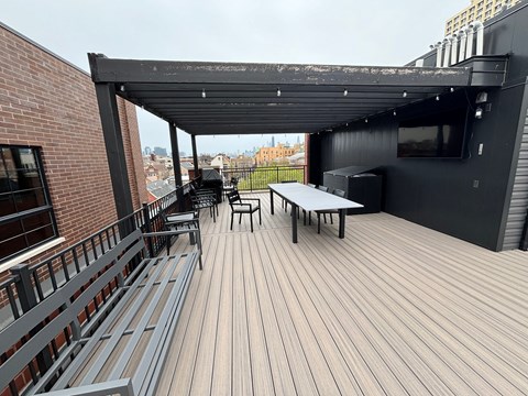 a rooftop patio with a black roof and a table and chairs