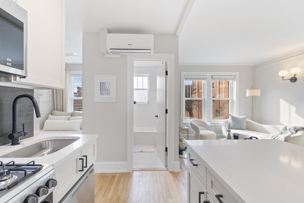 an open kitchen and living room with white cabinets and a white counter top
