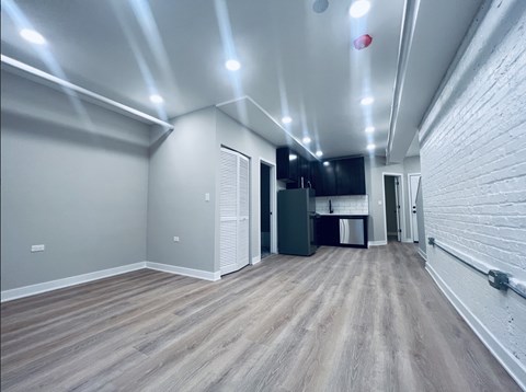 A spacious room with wooden flooring and white walls.