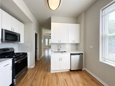 A kitchen with white cabinets and a black stove top oven.