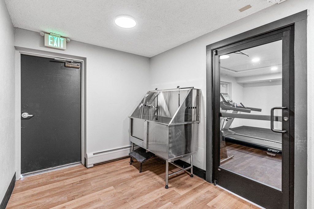 a gym with a treadmill and a door to a room with a exam room