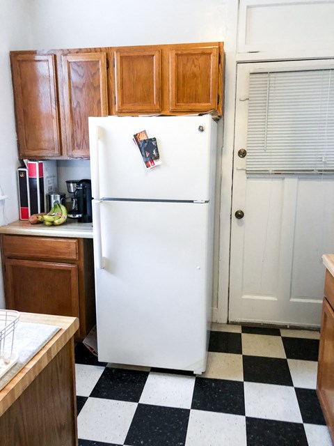 a kitchen with a refrigerator and wooden cabinets