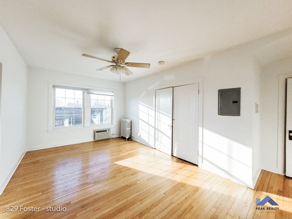 an empty living room with wood floors and a ceiling fan