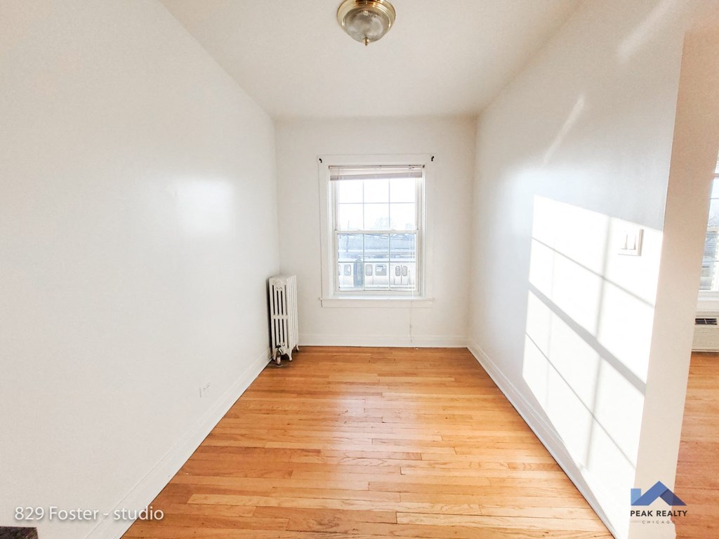 an empty room with wood floors and a window