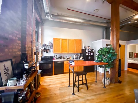 A kitchen with wooden floors and a brick wall.