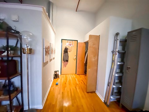 A hallway with a wooden floor and a ladder on the right side.